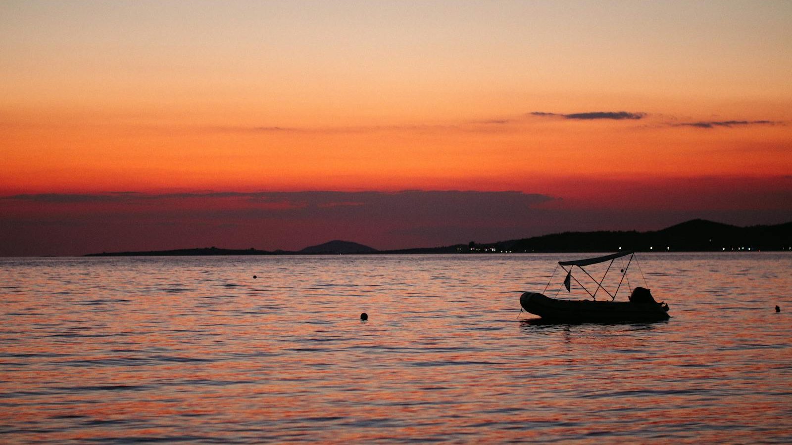 Silhouette of a boat at sunset on calm waters in Toroni, Greece. Perfect twilight tranquility.