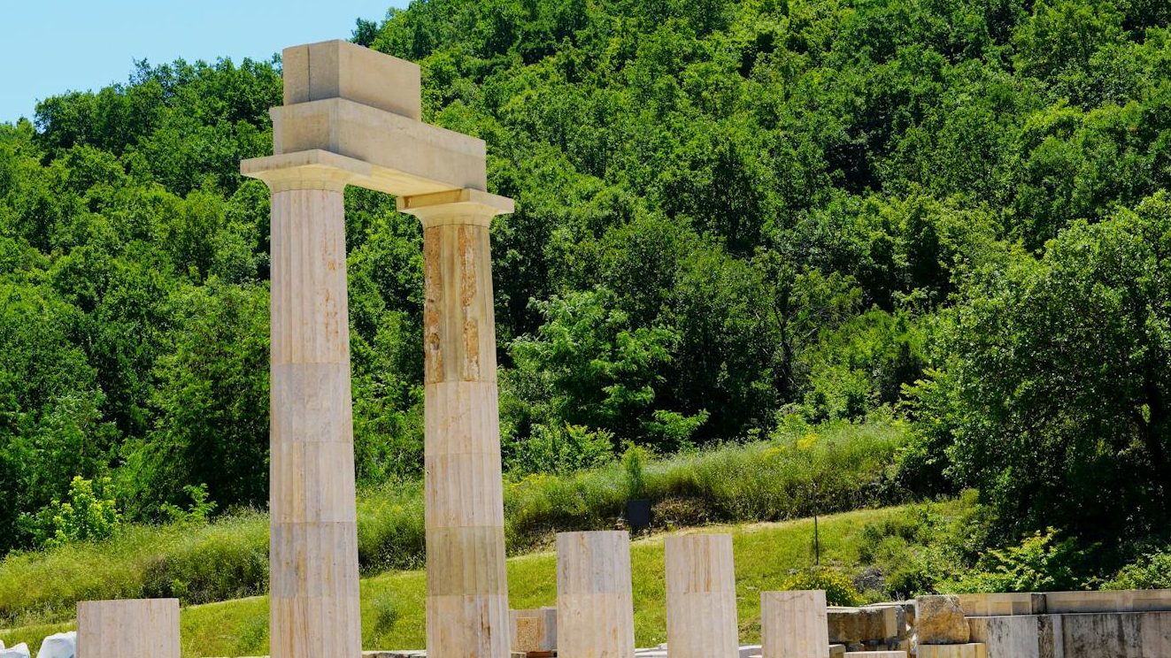 Classical stone columns set against a lush backdrop in Vergina, Greece.