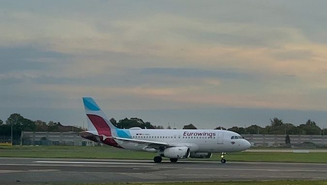 An airplane on a runway with a cloudy sky.
