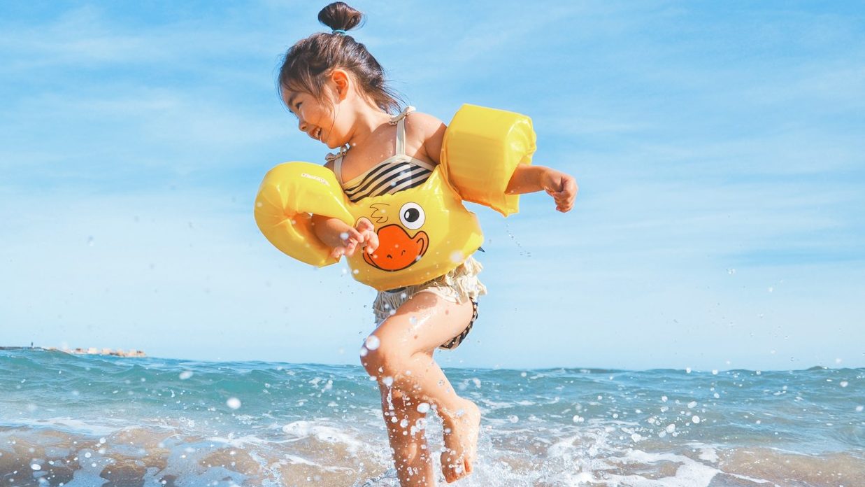 girl playing beside body of water during daytime