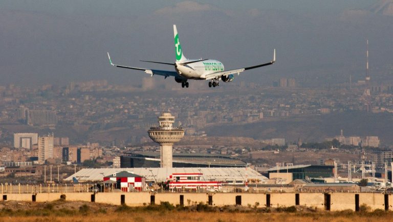 Airplane landing at an airport with control tower.